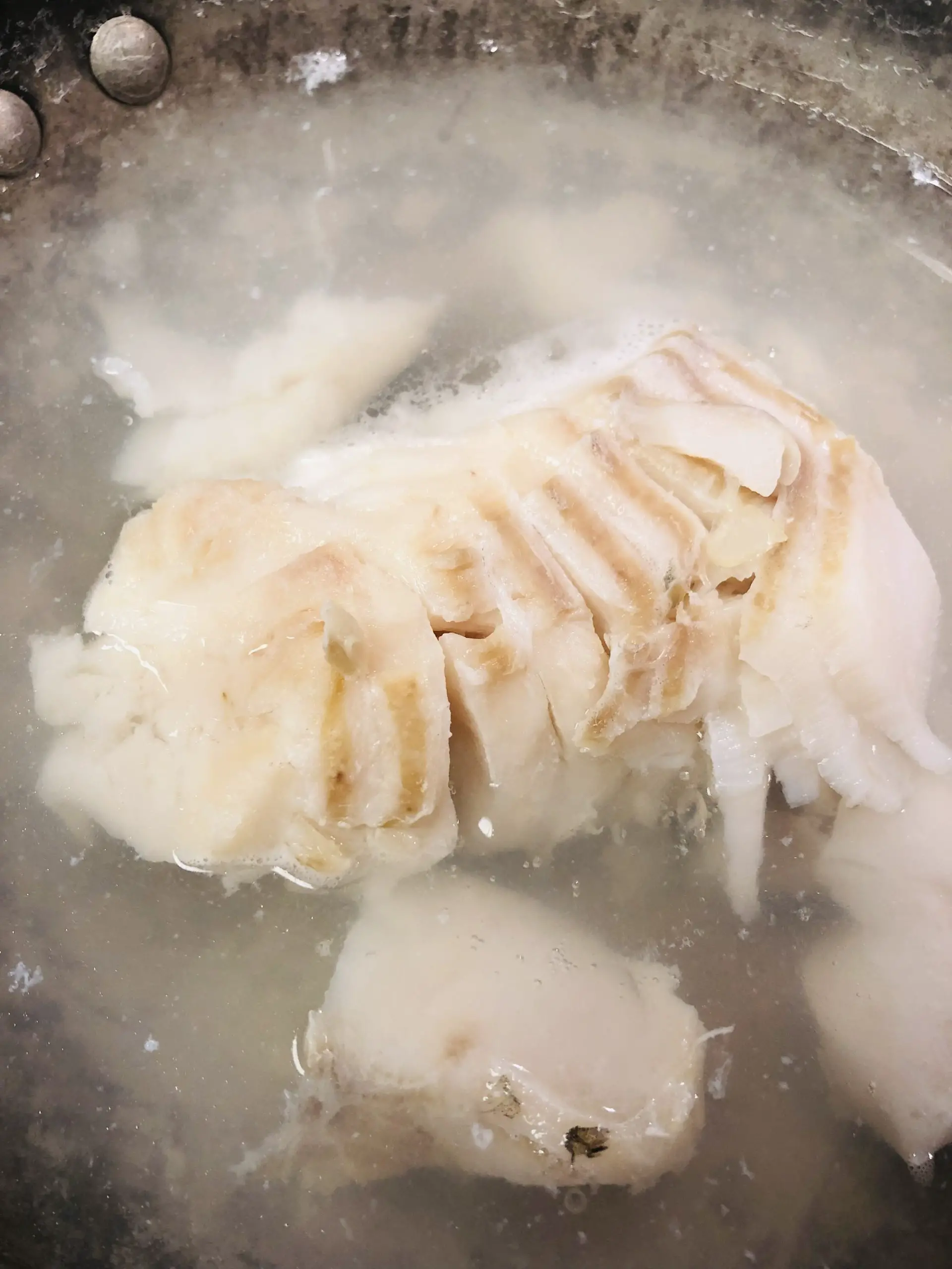 flaky cod in water in a skillet