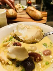 icelandic fish stew with fish on a spoon and baguettes and salad in the background