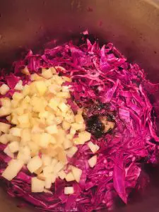 Sliced red cabbage, diced applies, and brown sugar in a pot