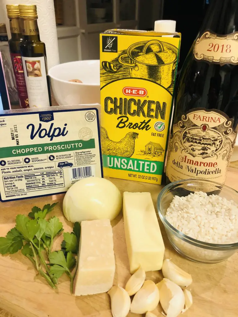 ingredients for risotto including Amarone wine, rice, chicken broth, onion, butter, garlic, Parmigiano Reggiano, parsley, and chopped proscuitto