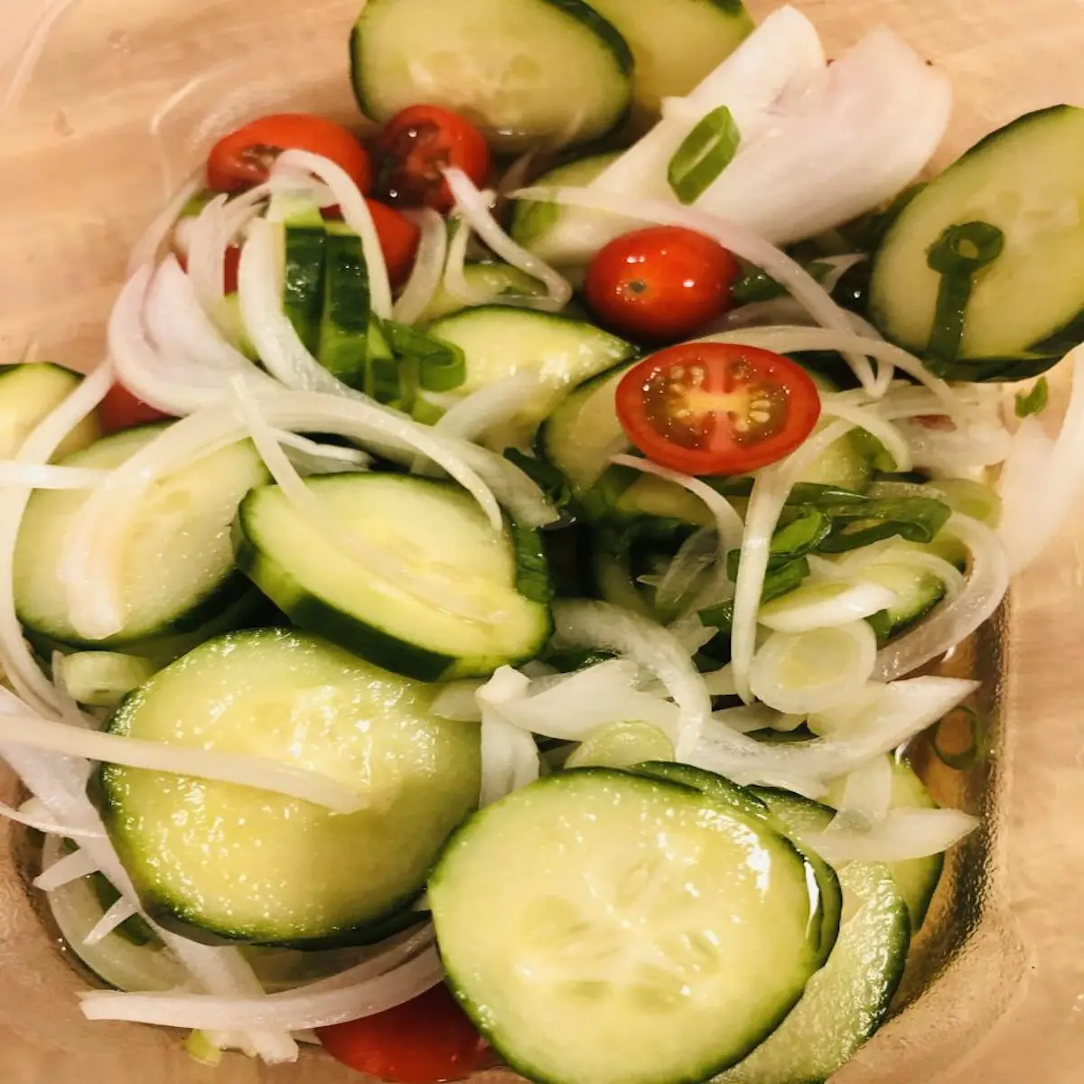 cucumbers, cherry tomatoes, onions, and green onions making up a thai cucumber salad