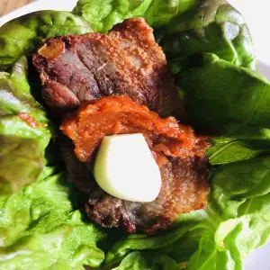 fried pork belly in a soft lettuce leaf topped with ssamjang and a garlic clove