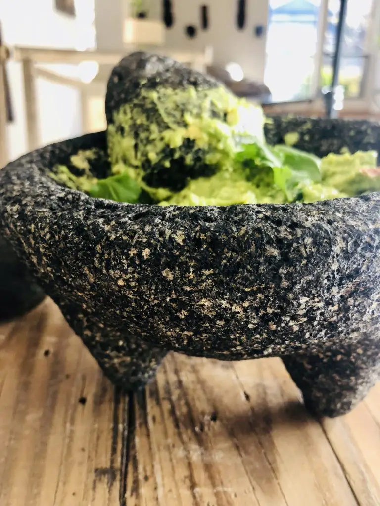 Guacamole in a molcajete with a pestle and cilantro as garnish