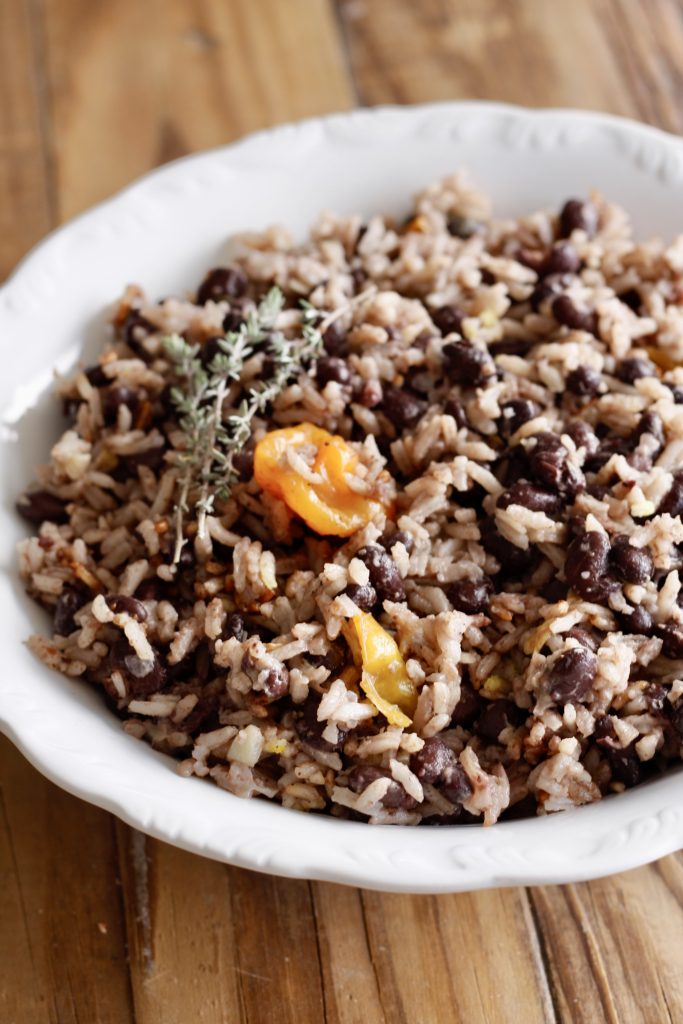 Haitian Rice and Beans garnished with thyme and scotch bonnet in a white bowl
