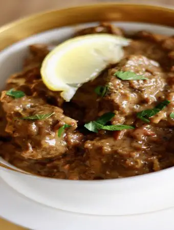 Italian Braised Lamb In Egg And Lemon Sauce in a gold rimmed bowl