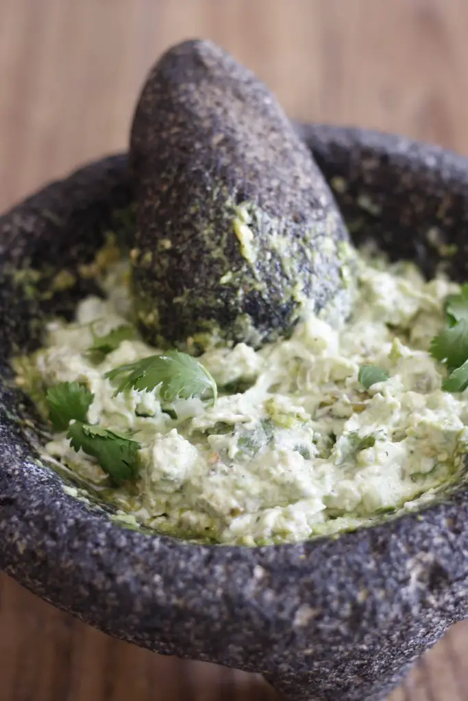 Guacamole in a molcajete with a pestle garnished with cilantro