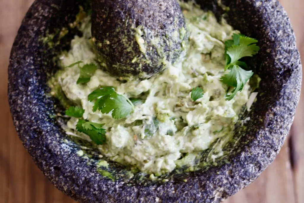 Guacamole in a molcajete with a pestle and garnished with cilantro