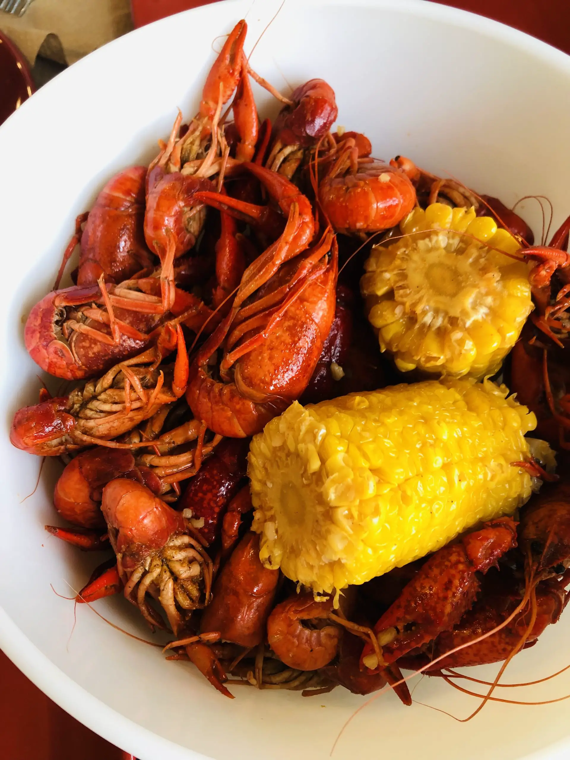 Crawfish and corn on the cob in a white bowl