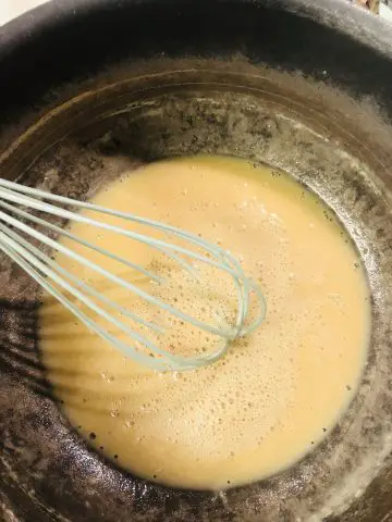 a roux with a blue whisk in a saucepan