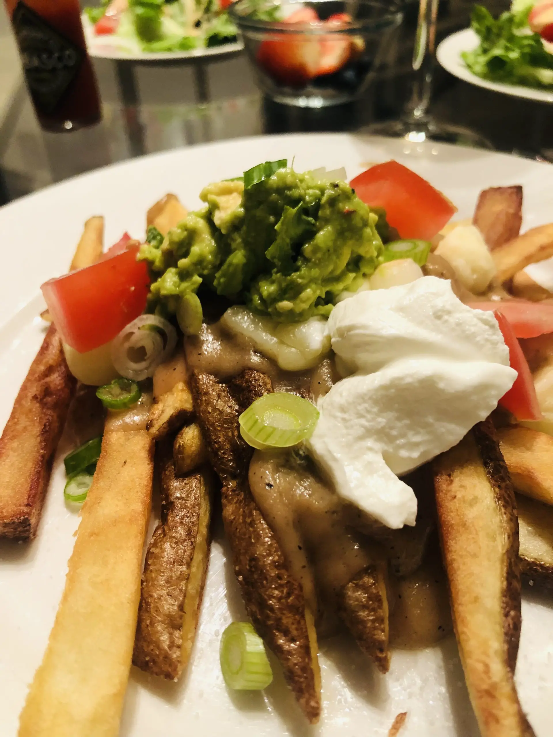 Poutine with guacamole, sour cream, and tomatoes