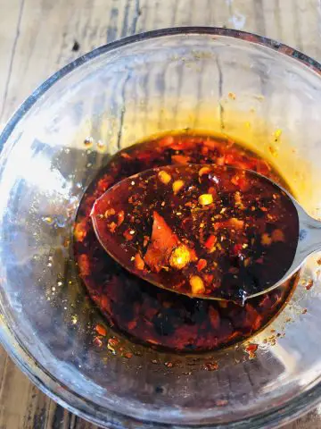 spicy chili sauce in a glass bowl with some in a spoon