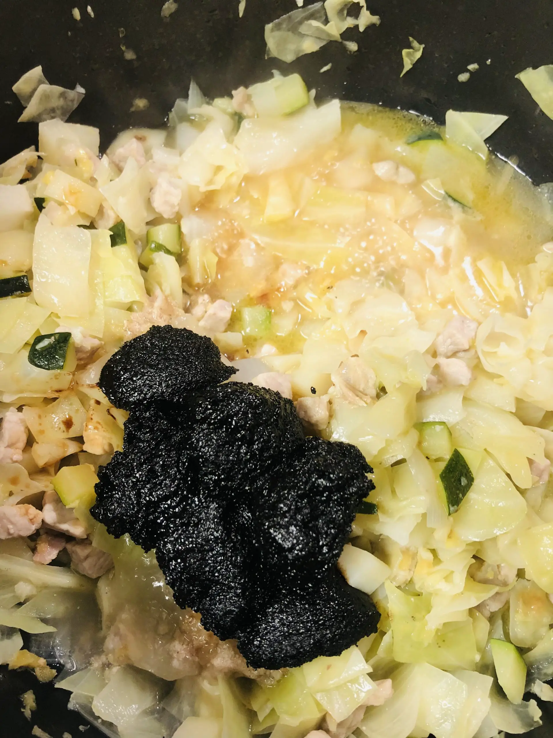 vegetables including cabbage, chicken broth, pork, and black bean paste in a pan