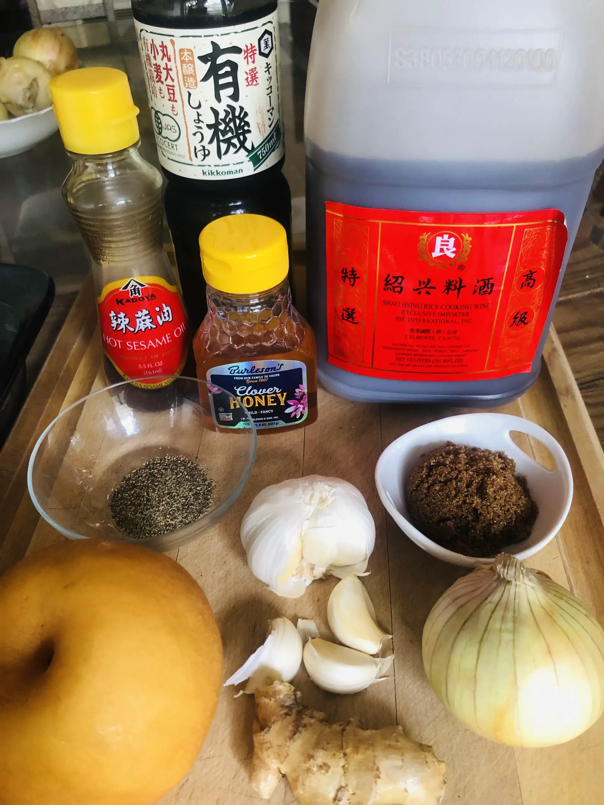 Asian pear, black pepper in a glass bow, ginger, garlic, onion, brown sugar in a white dish, Shaoxing rice wine, honey, hot sesame oil, and soy sauce