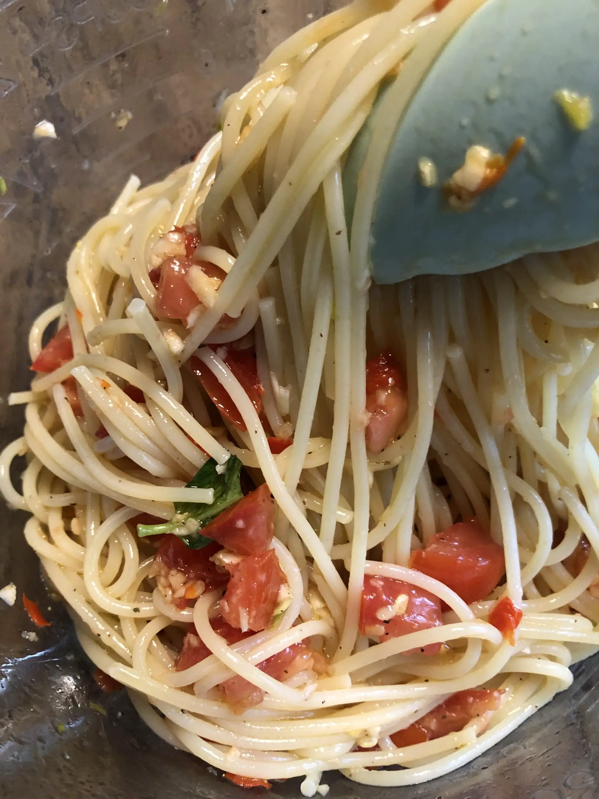 spaghetti with diced tomatoes, basil and garlic with blue tongs