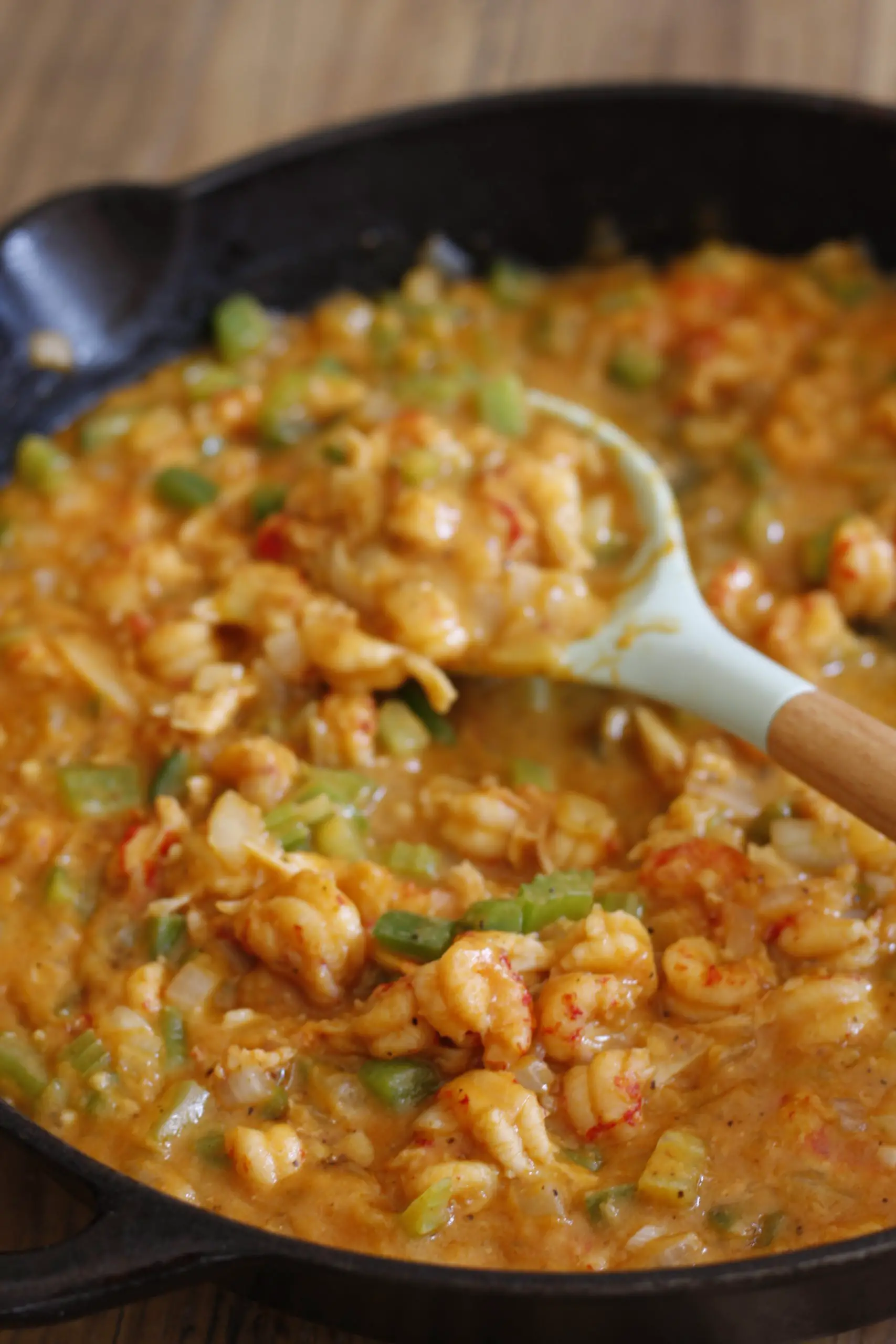 Crawfish Étouffée in a cast iron pan with a blue silicone spoon