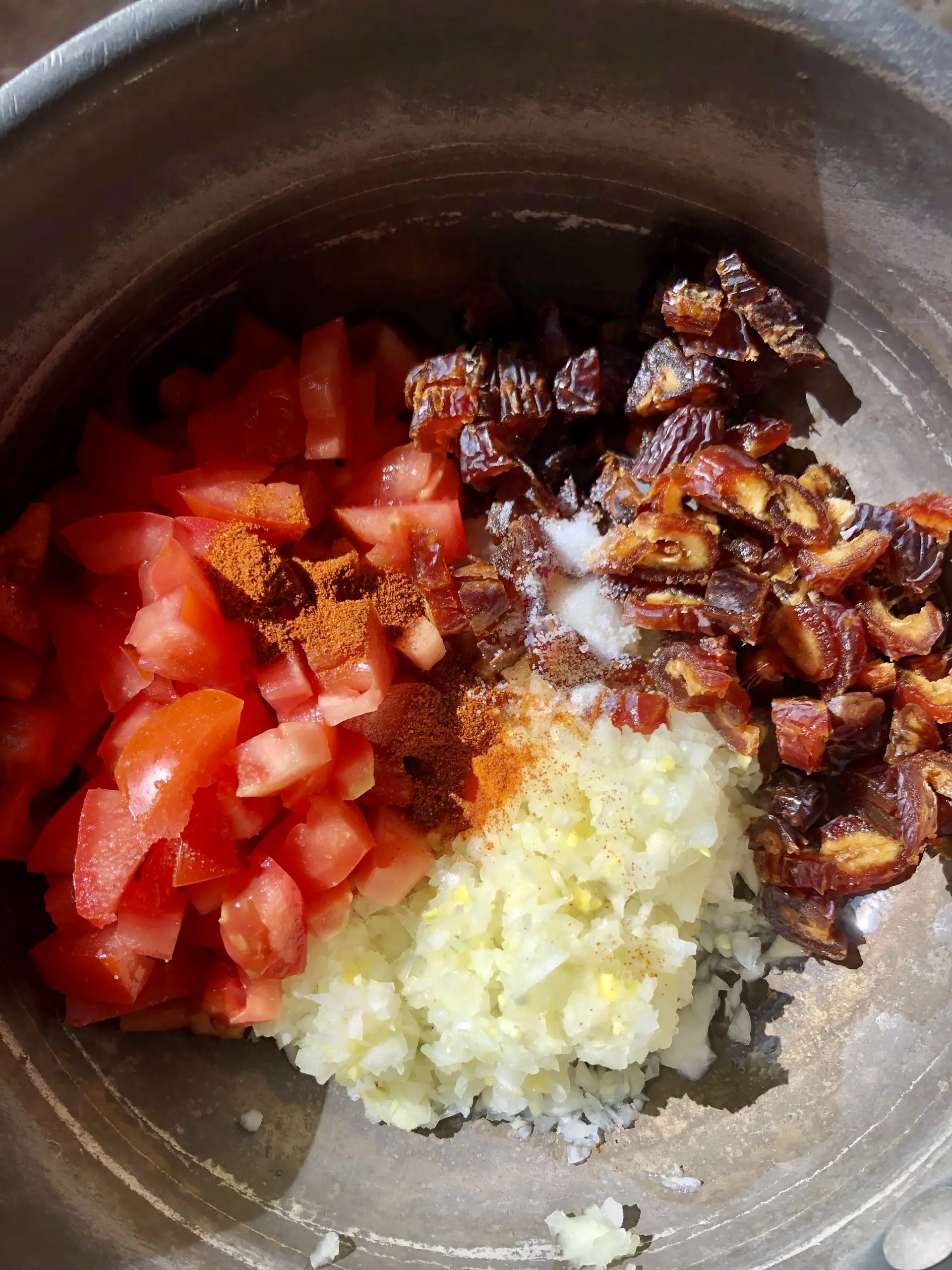 Diced tomatoes, diced onions, diced dates, minced ginger and garlic and spices in a saucepan