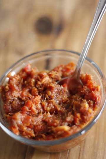Tomato and date chutney in a glass bowl with a spoon