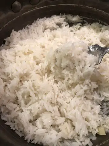 Cooked fluffy rice in a pan with a fork