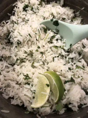 Cilantro Lime Rice with a blue spoon and slices of lime
