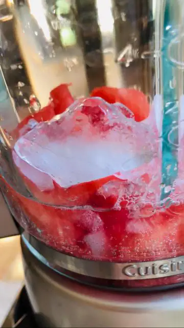 Crushed ice and watermelon cubes in a blender.