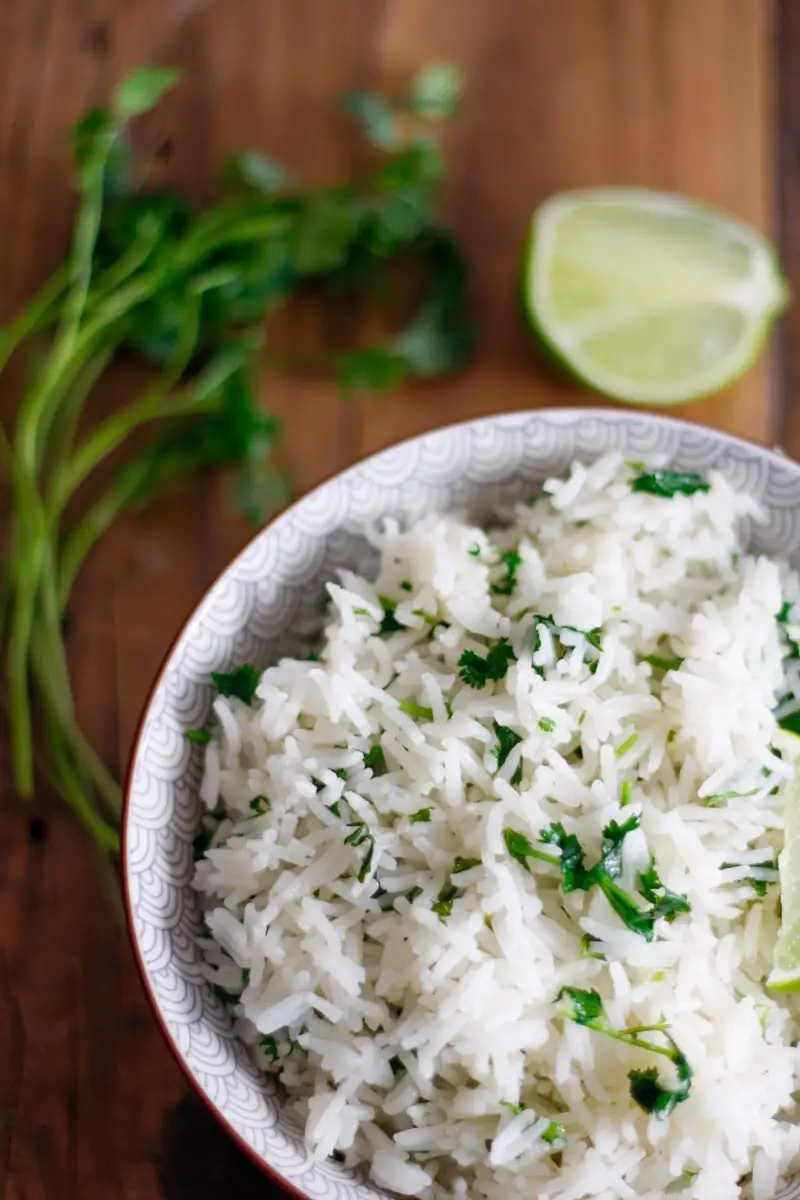 Cilantro Lime Rice in a bowl with cilantro and lime in the background