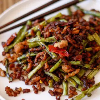 Chinese Long Beans With Pork on a white plate with chopsticks in the background.