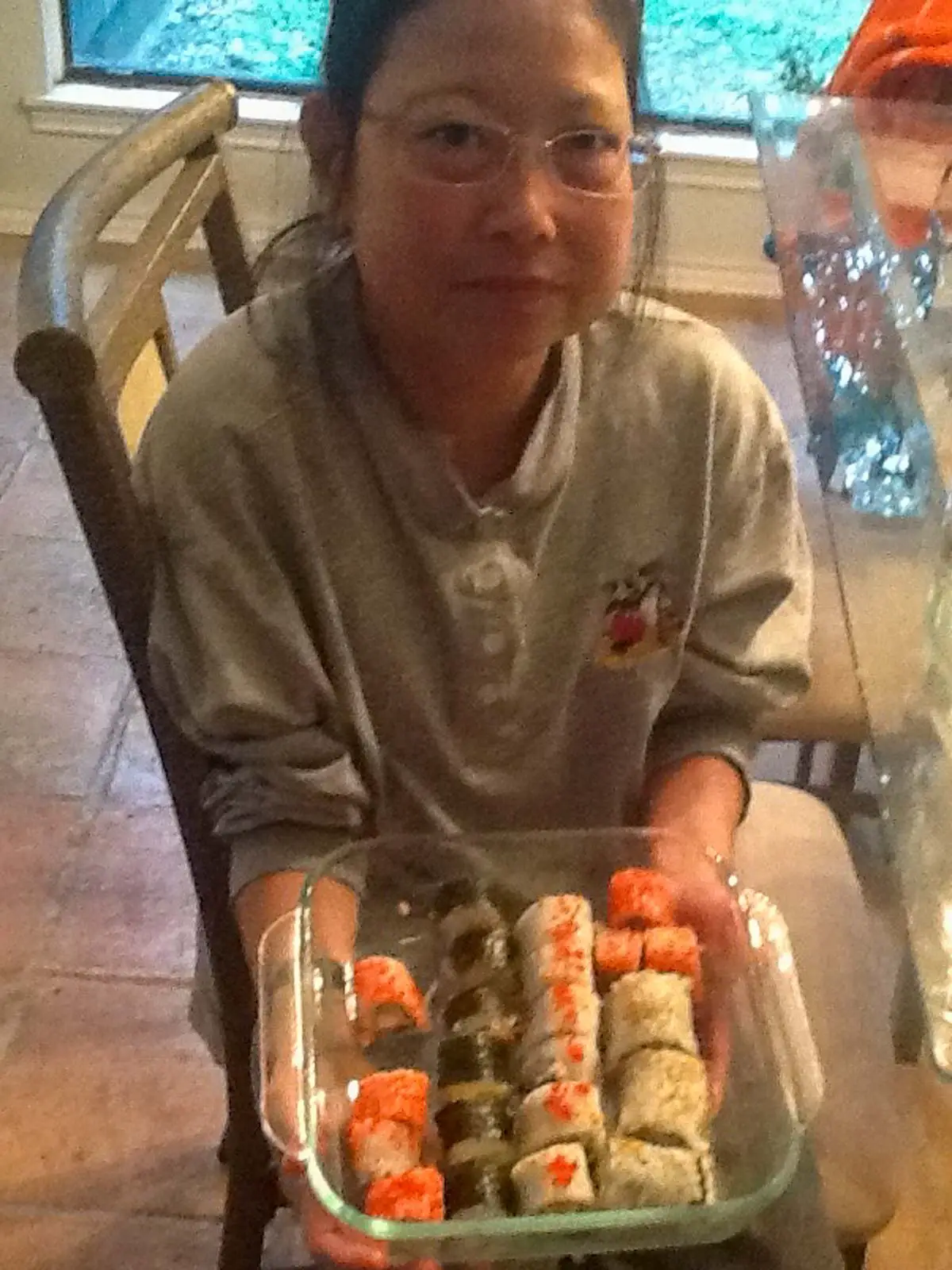 My sister Tami holding a glass dish with different colored and types of sushi
