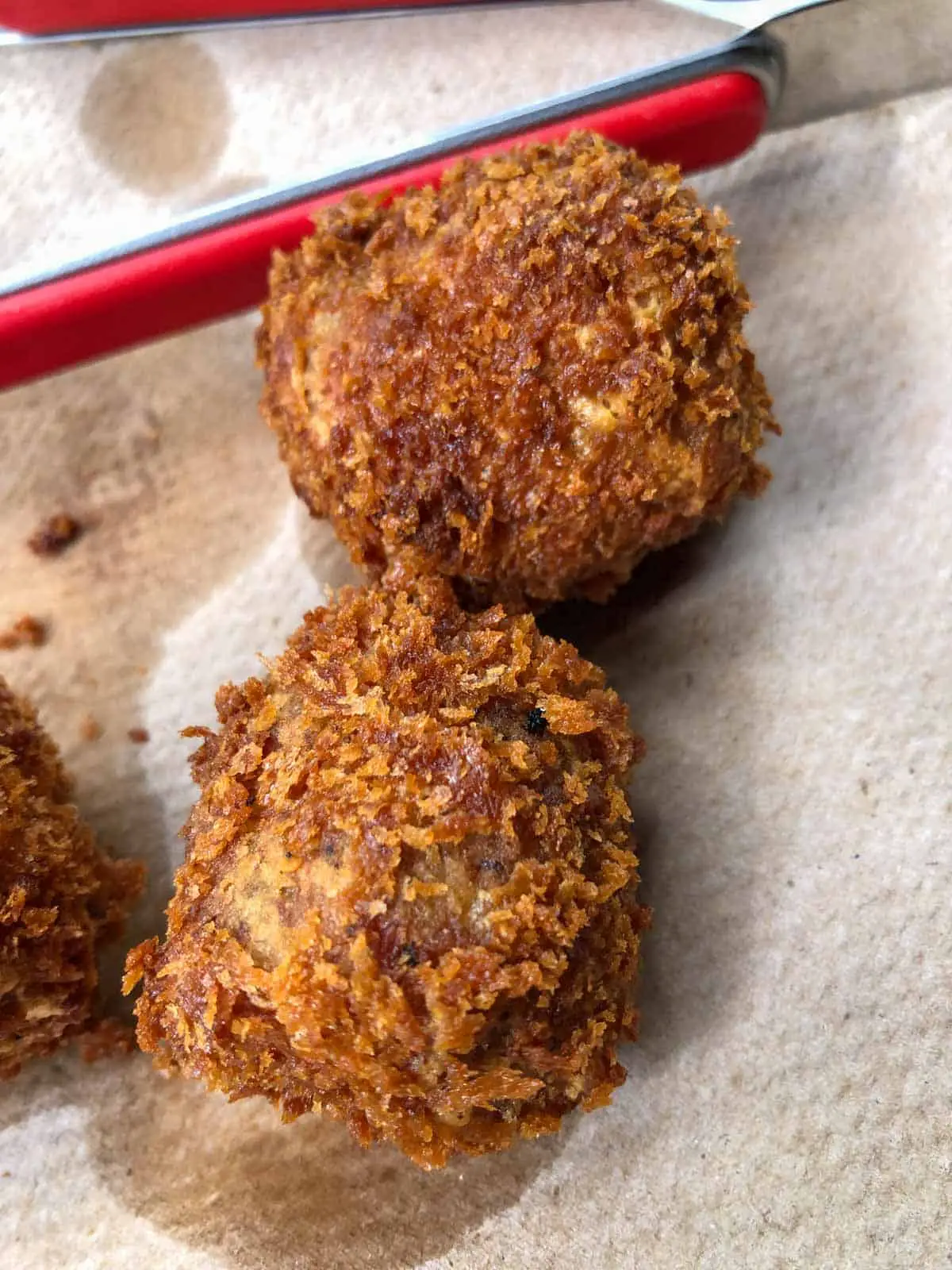 Boudin Balls draining on paper towels with a pair of red tongs behind them