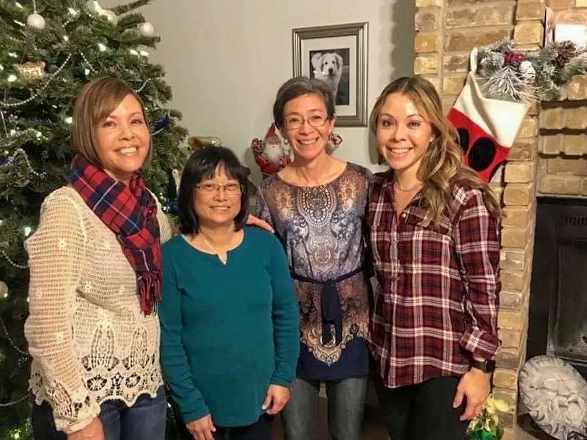 Four sisters standing together in front of a Christmas tree