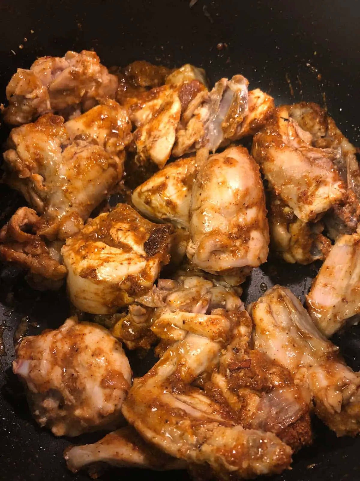 Chicken pieces coated with spices in a pot