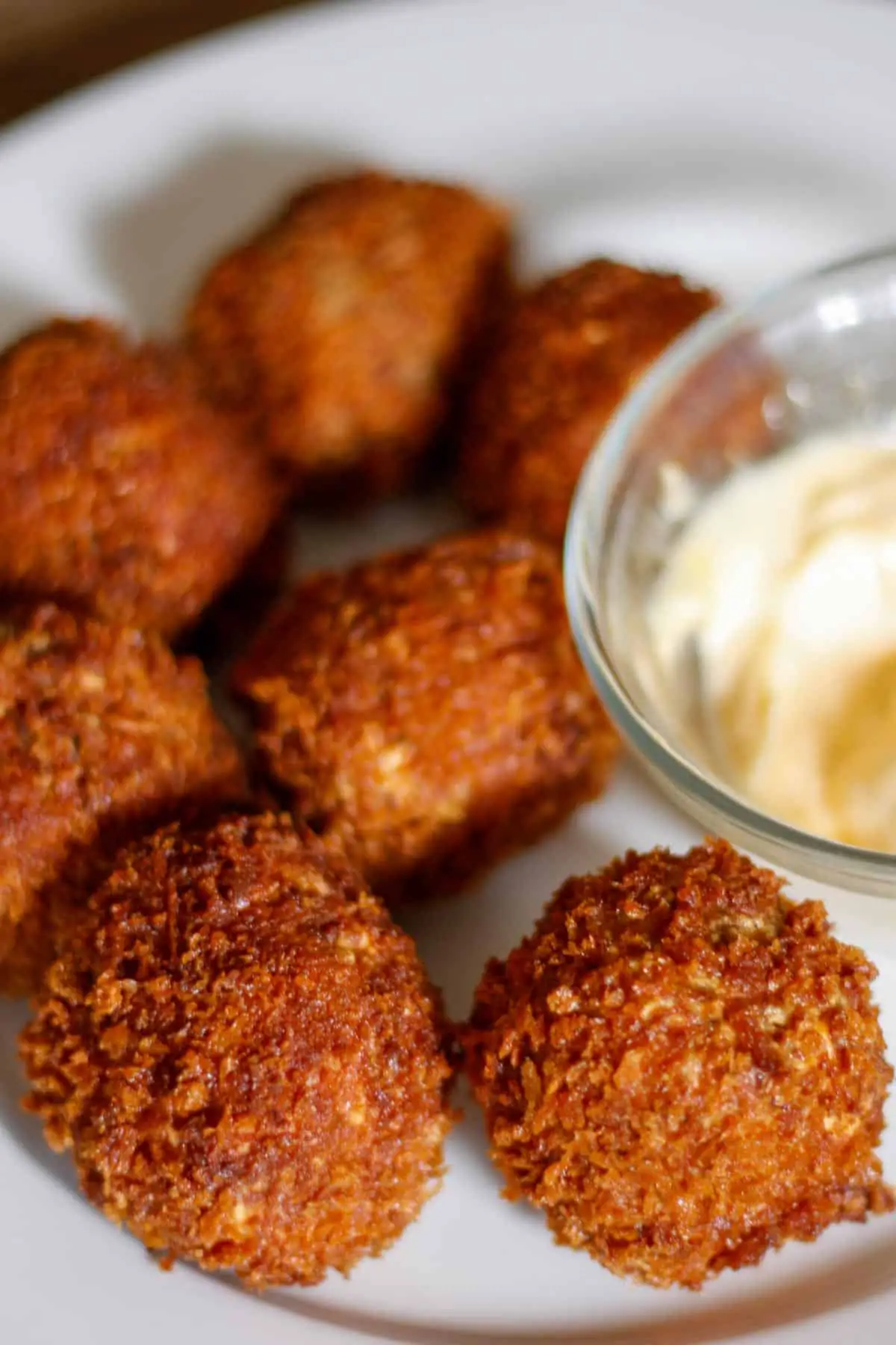 Boudin Balls on a white plate with mayo in a glass bowl