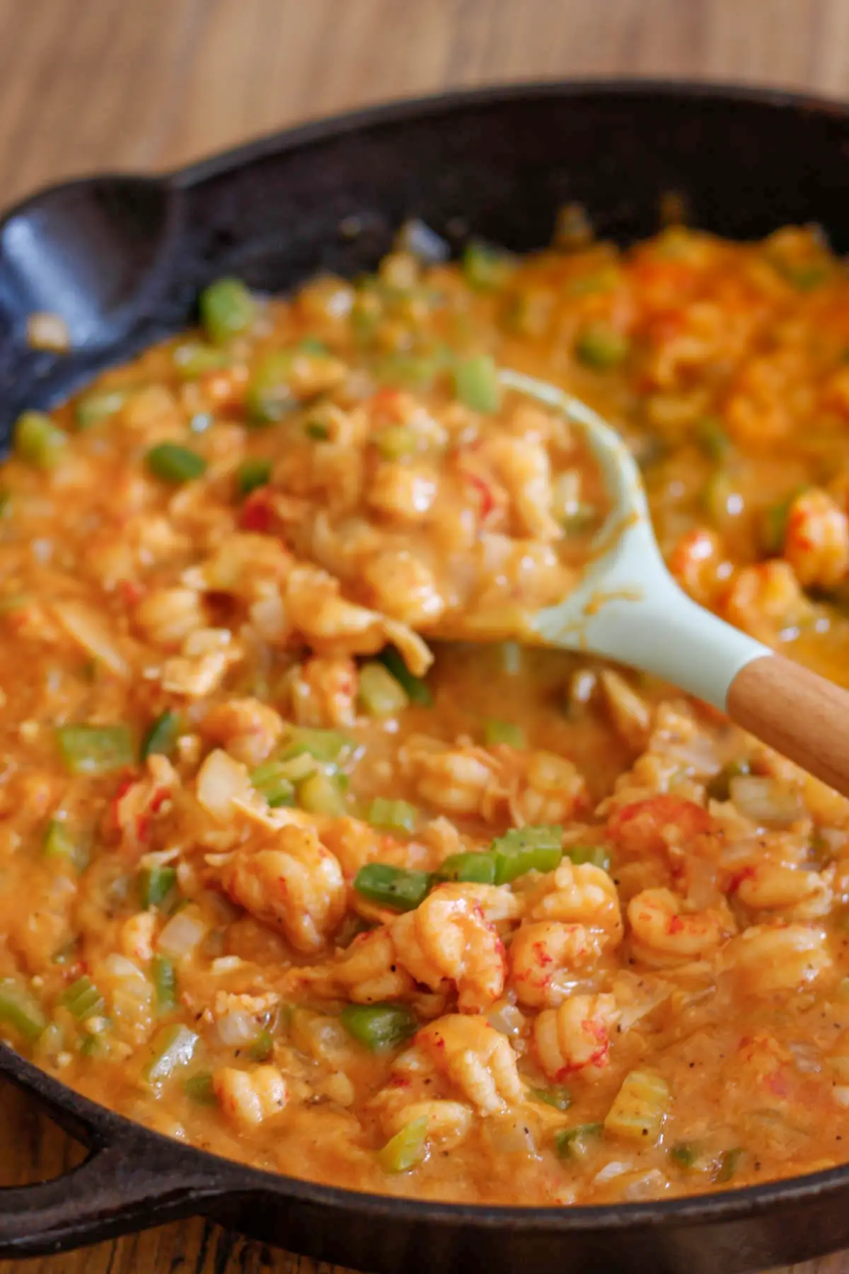 Crawfish Étouffée in a cast iron pan with a blue silicone spoon