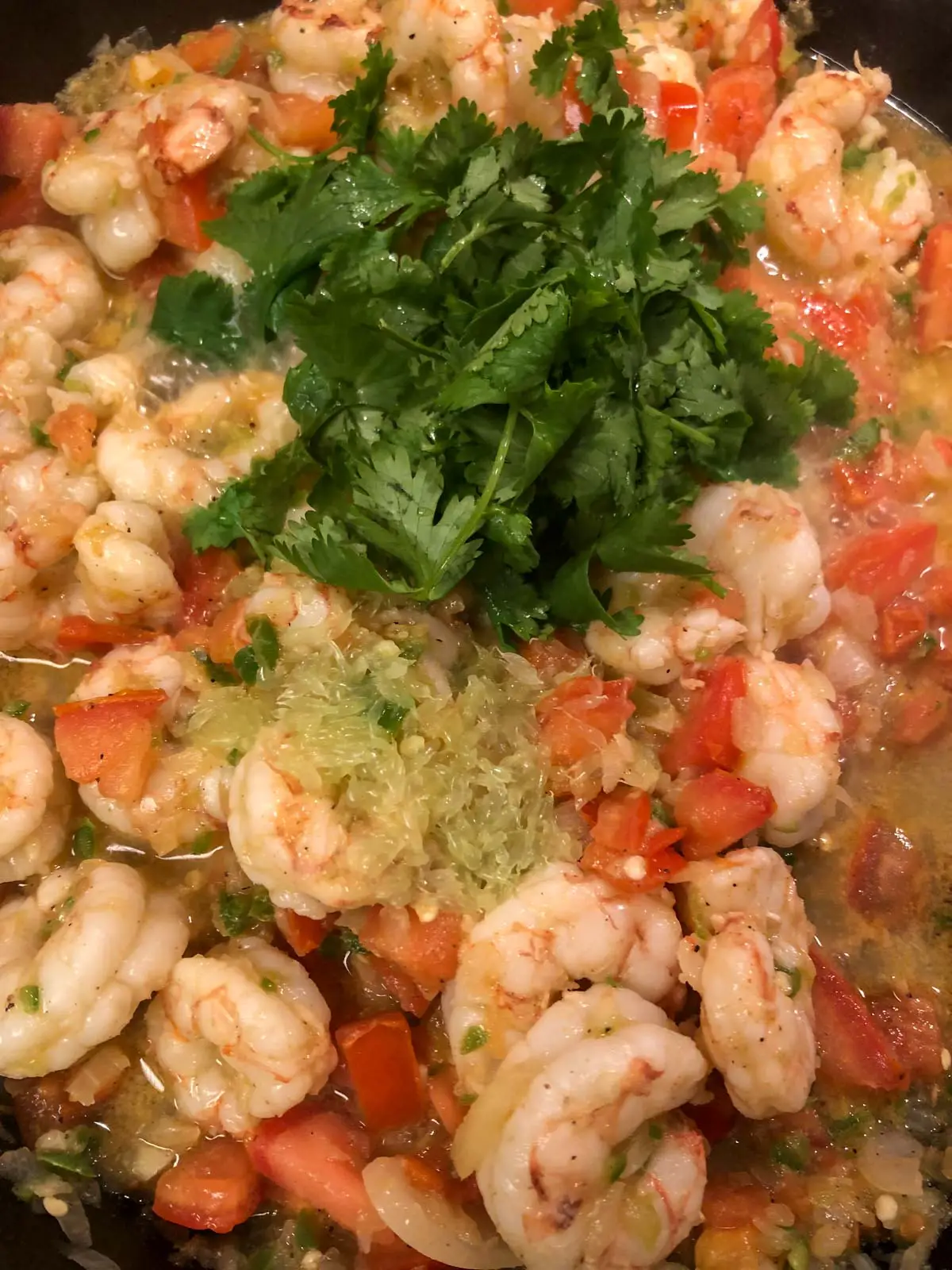 Shrimp with cilantro , diced tomatoes, minced onion and chilies, juices, and lime juice in a cast iron pan.
