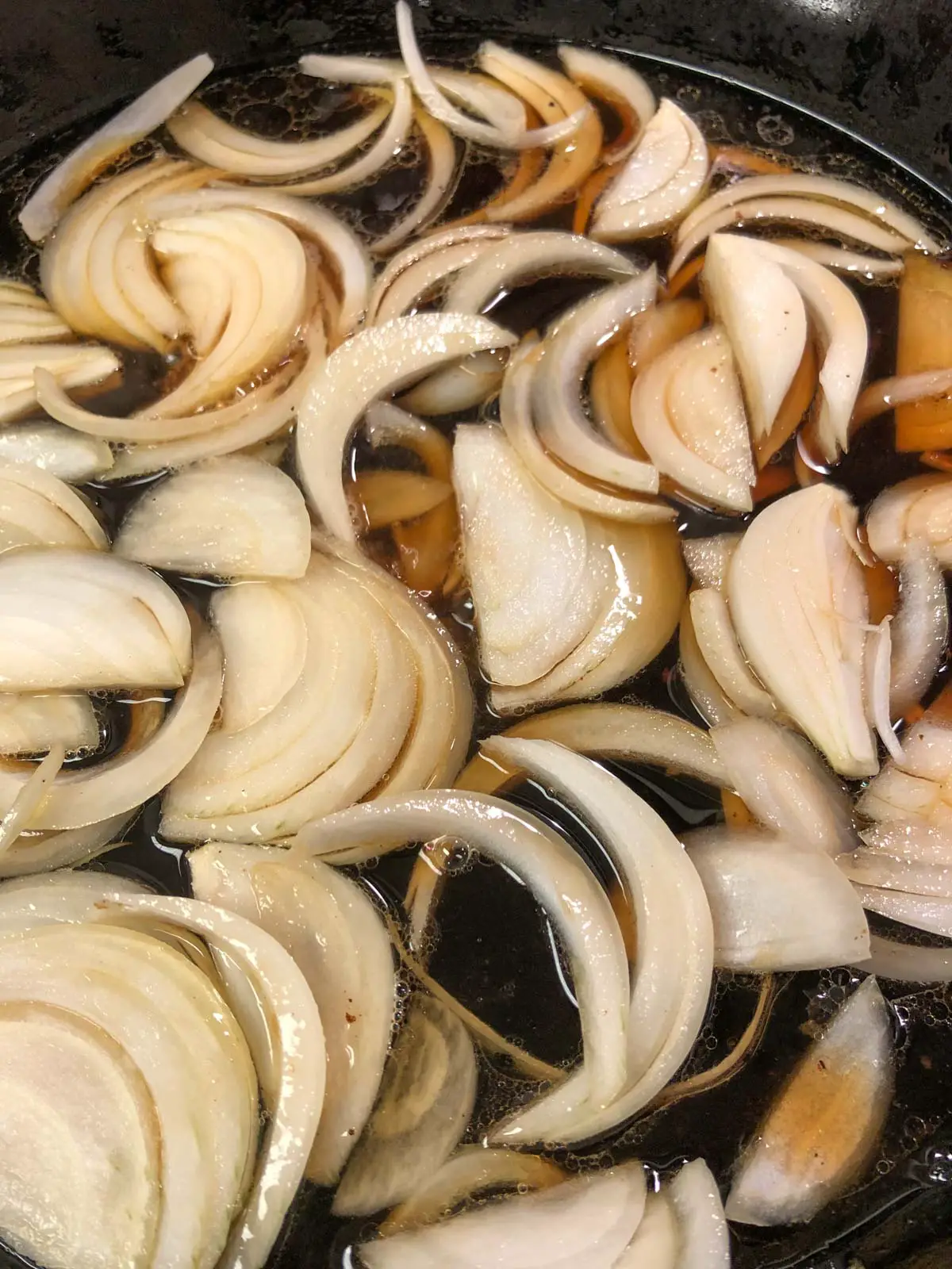 Slices of onion simmering in a soy based broth.