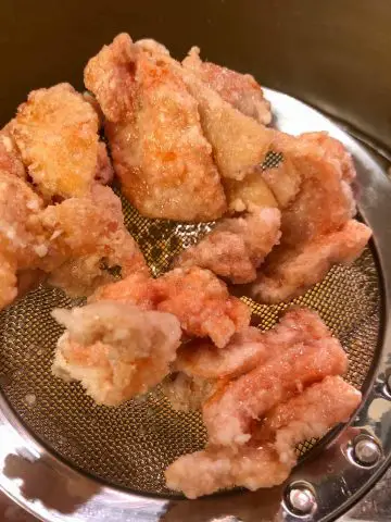 Pieces of bite sized fried chicken on a kitchen utensil.