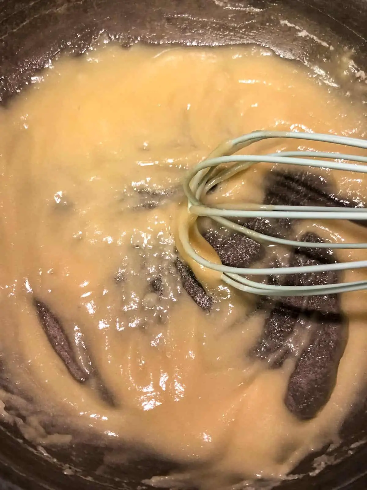 Butter and flour roux in a saucepan with a blue whisk.
