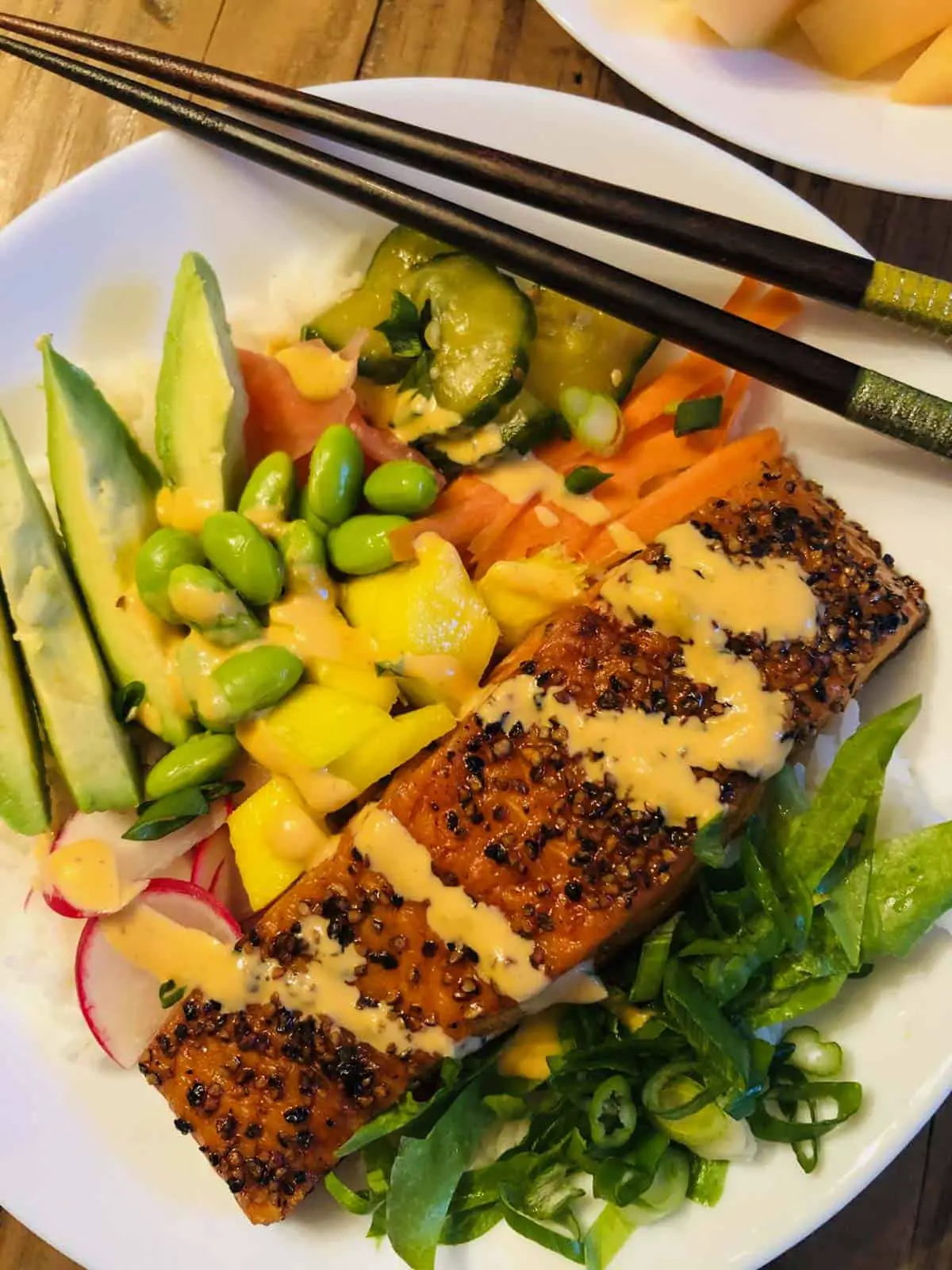 Salmon Rice Bowl with vegetables in a white bowl with chopsticks