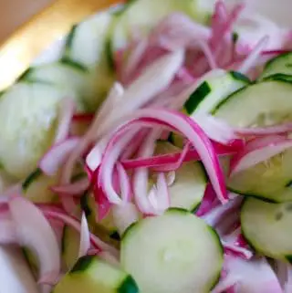 Southern Cucumber Salad which is slices of cucumber and slices of red onion in a gold rimmed bowl.