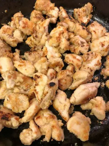 Chicken pieces which have been coated with egg and flour and have been cooked in a cast iron pan.