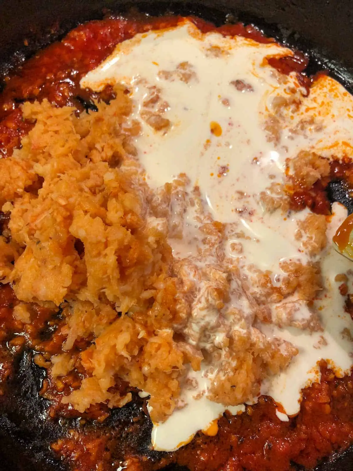 Tomato paste with minced shrimp and cream in a cast iron skillet.