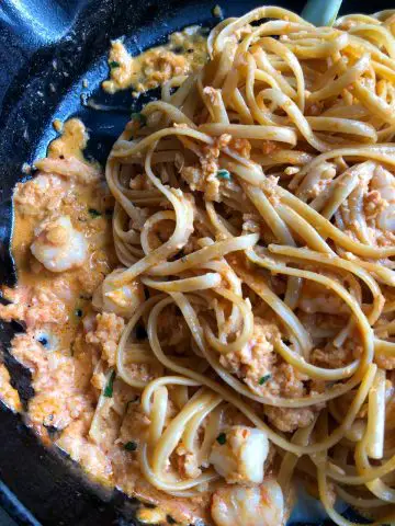 seafood pasta garnished with parsley in a cast iron skillet