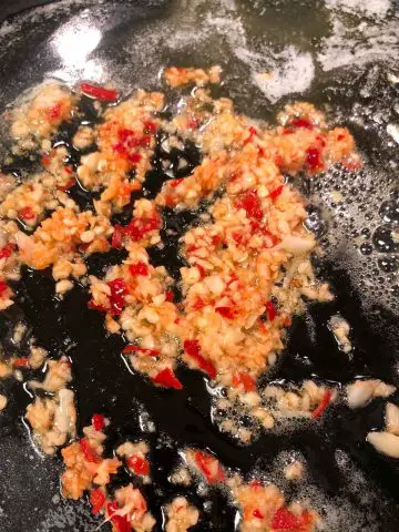 Minced garlic and minced chilies in a butter and olive oil sauce in a cast iron pan.