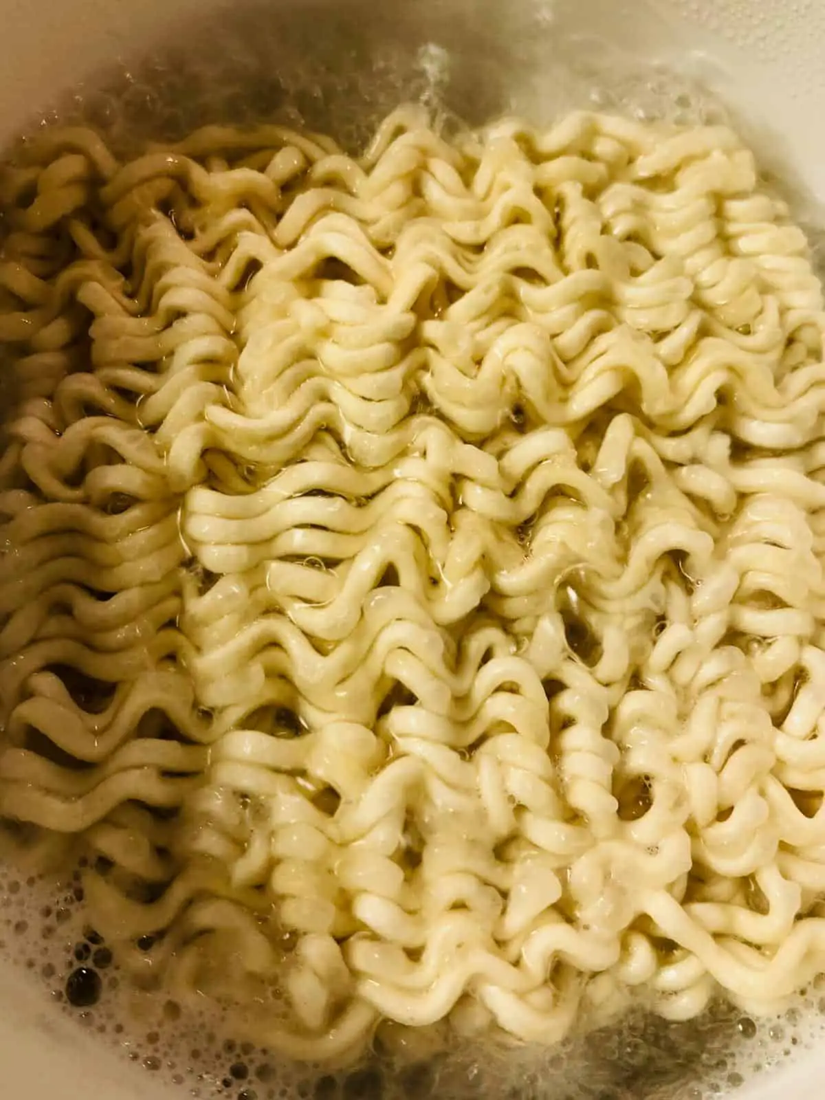 Noodles that are boiling in a kettle.