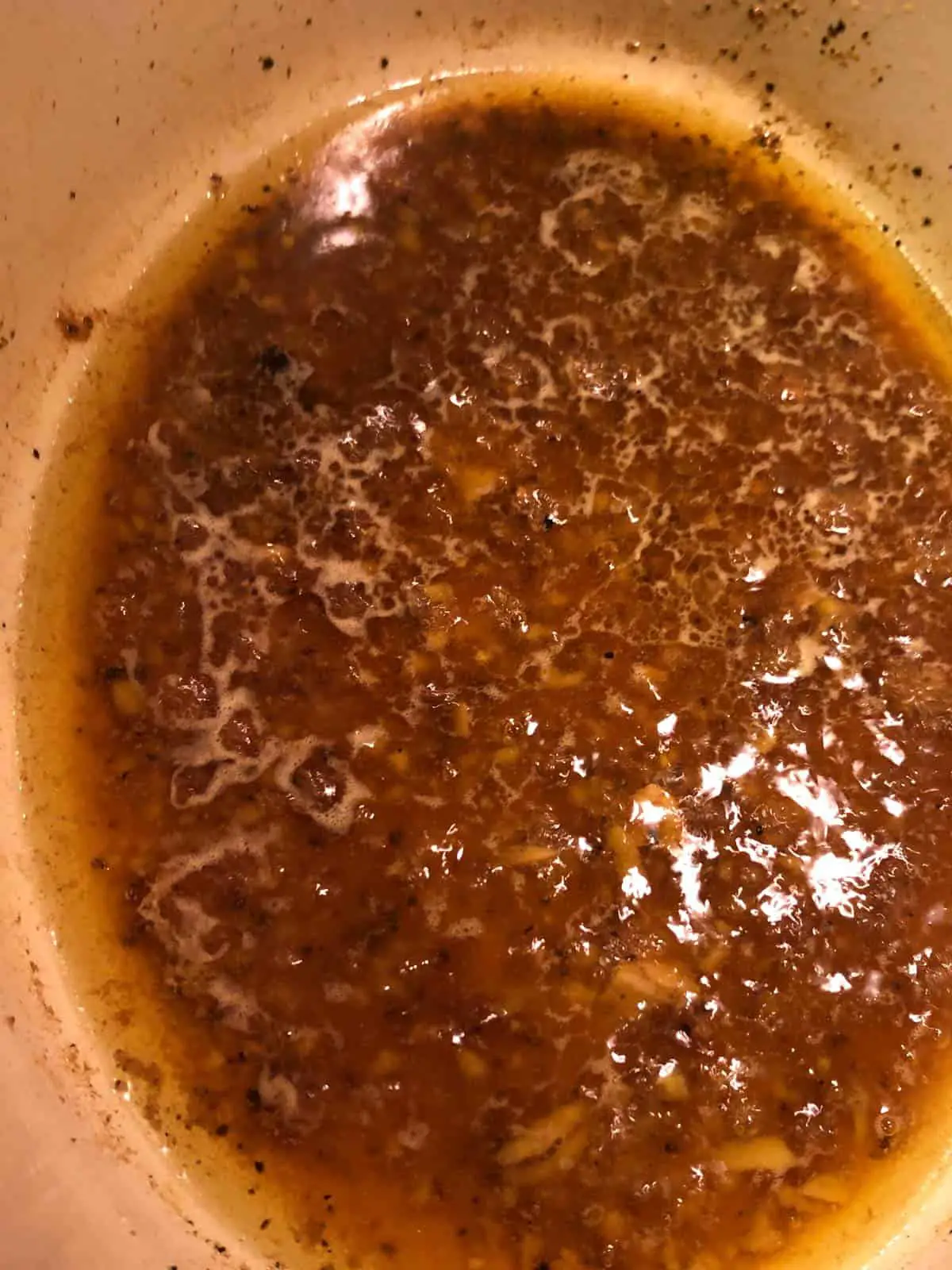 Deep brown colored braising sauce in a dutch oven.