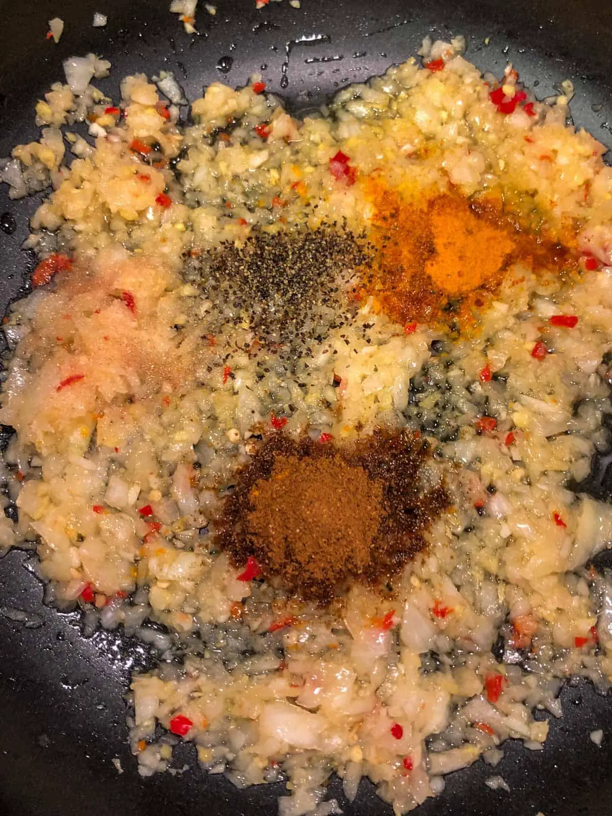Minced onion, garlic, ginger, and chilies, and salt, pepper, cayenne, turmeric, and garam masala in oil in a large skillet.