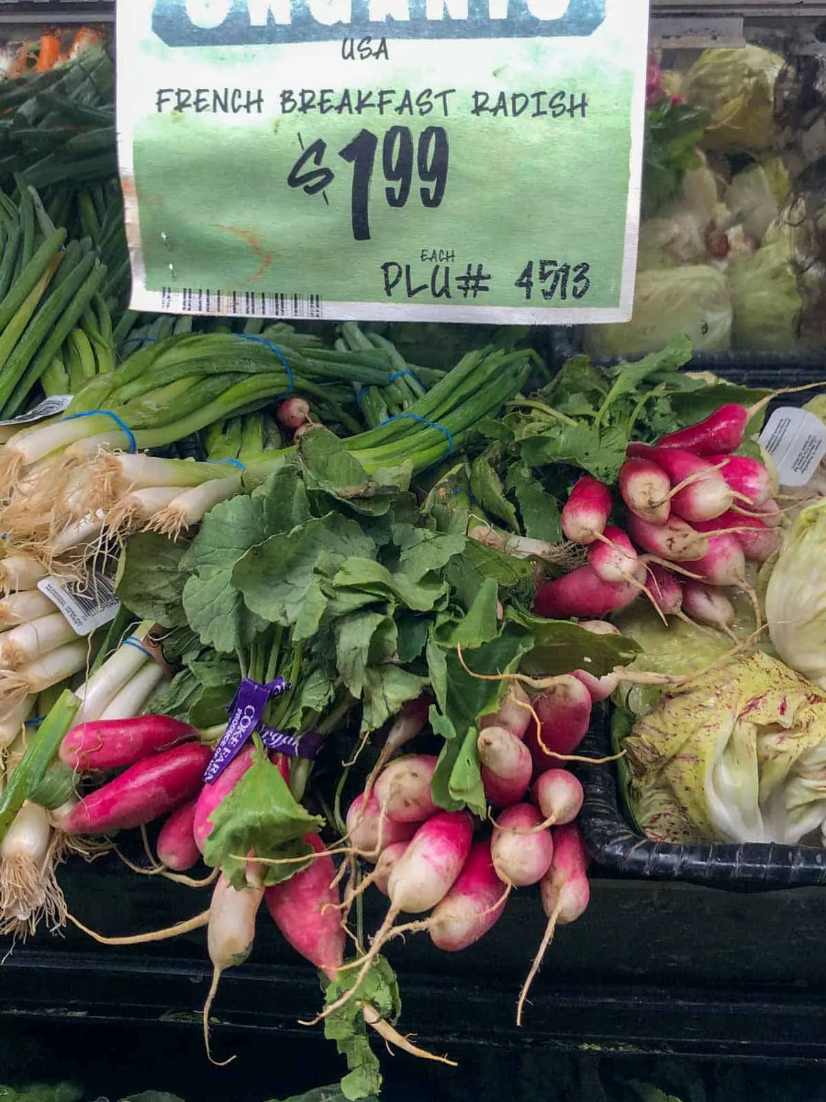 A display of French breakfast radishes in a grocery store with a sign showing that they are $1.99 per bundle.