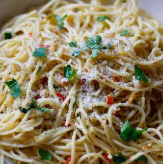 Spaghetti with bits of chili and garlic garnished with Italian parsley and grated Parmesan cheese.