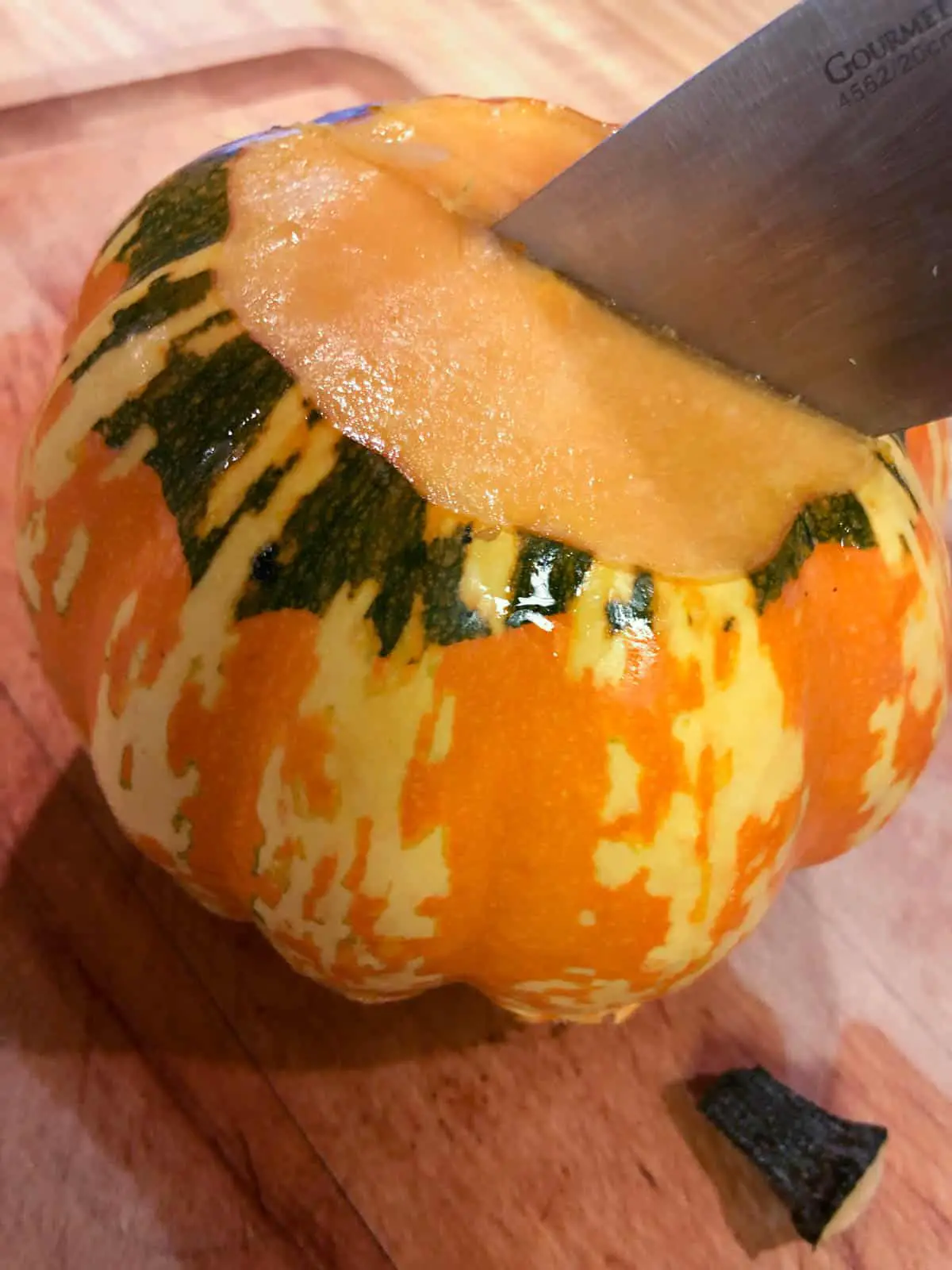 Carnival squash with the top cut off and a knife sticking out of it.
