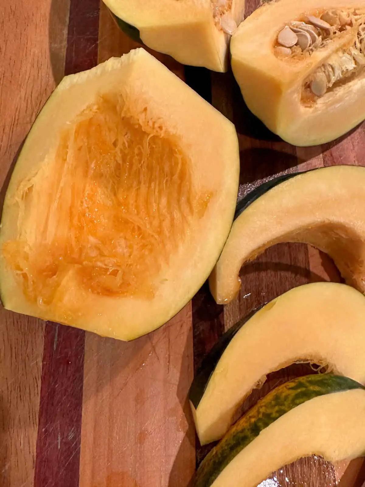 Wedges of acorn squash, a quarter portion of an acorn squash with seeds removed, and 2 large wedges of squash with seeds intact.