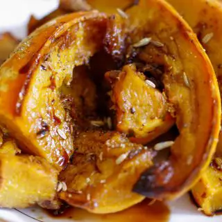 Wedges of carnival squash in a white gold rimmed bowl with fennel seeds and balsamic vinegar.